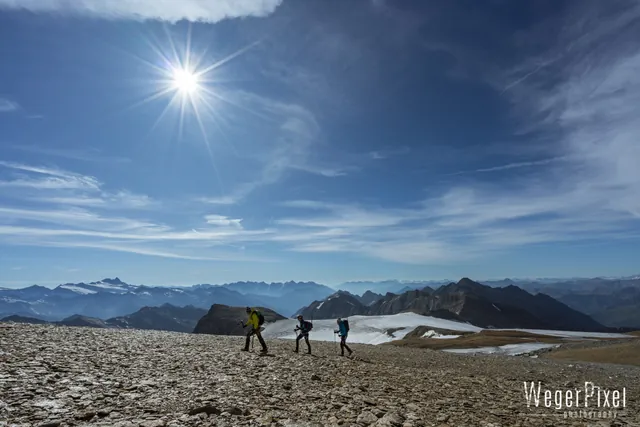 Drei Bergsteiger im Geröll in der Venedigergruppe, Sonne über den Gletschern