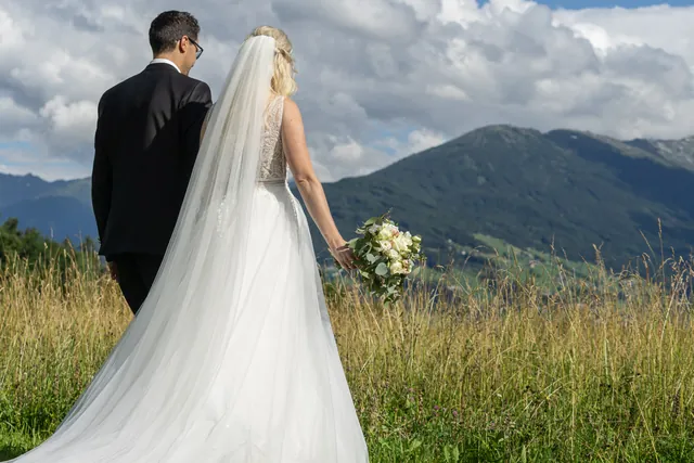 Brautpaar von hinten in der Wiese mit Blick auf die Berge