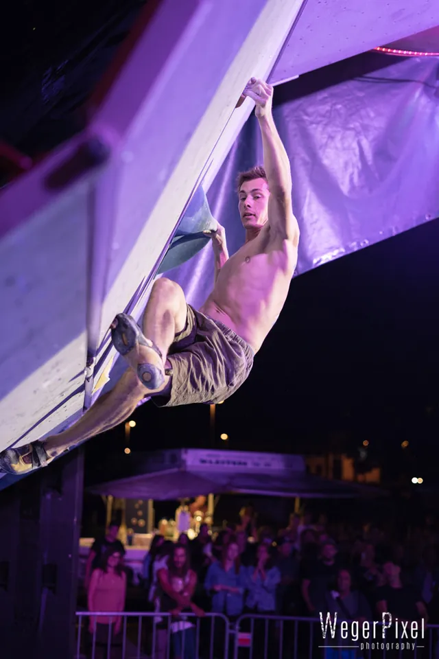 Kletterer im Überhang beim KIOT Bouldercup in Lienz, darunter das Publikum