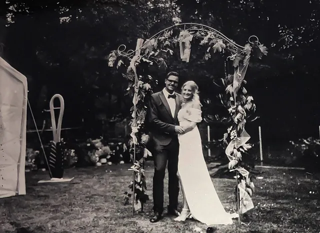 Hochzeitspaar unter einem Blumenbogen, aufgenommen im Kollodium-Nassplattenverfahren